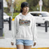 Nova Scotia hoodie with lighthouse coastal fishing village graphic worn by model outdoors near ocean cliffs