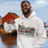 Nova Scotia hoodie with lighthouse coastal fishing village graphic worn by model outdoors near ocean cliffs