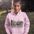 Nova Scotia hoodie with lighthouse coastal fishing village graphic worn by model outdoors near ocean cliffs