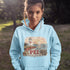 Person wearing a light blue hoodie with a lighthouse design and 'PEI' text outdoors.