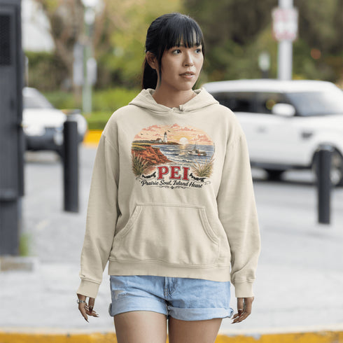 Woman wearing a beige hoodie with a scenic design and 'PEI' text, standing on a street.