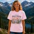 Woman wearing a pink t-shirt with 'Peak Seeker Wanderer' design in a mountainous landscape.