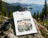 White t-shirt with 'Peak Seeker Wanderer' design on a rock with scenic background
