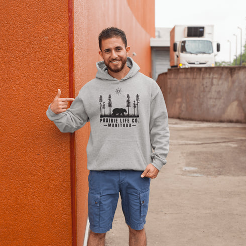 Our Prairie Life Co. Signature Hoodie captures the essence of the wilderness, featuring a striking design of a bear roaming among tall trees.