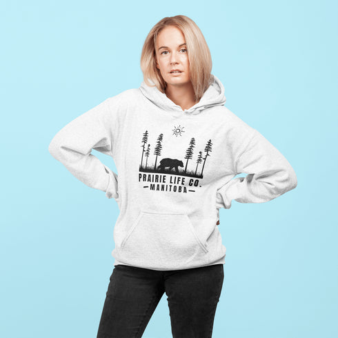 Our Prairie Life Co. Signature Hoodie captures the essence of the wilderness, featuring a striking design of a bear roaming among tall trees.