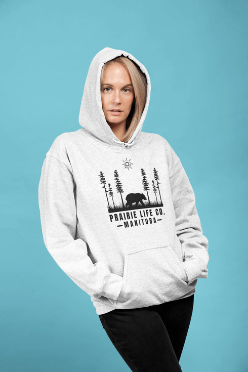 Our Prairie Life Co. Signature Hoodie captures the essence of the wilderness, featuring a striking design of a bear roaming among tall trees.