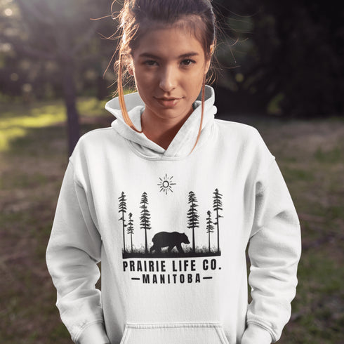 Our Prairie Life Co. Signature Hoodie captures the essence of the wilderness, featuring a striking design of a bear roaming among tall trees.