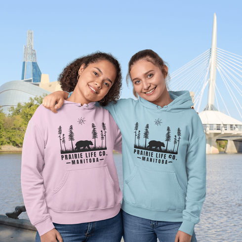 Our Prairie Life Co. Signature Hoodie captures the essence of the wilderness, featuring a striking design of a bear roaming among tall trees.