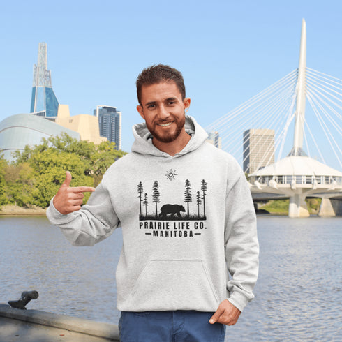 Our Prairie Life Co. Signature Hoodie captures the essence of the wilderness, featuring a striking design of a bear roaming among tall trees.