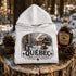White hoodie with Québec maple syrup cabin design on a wooden stump with maple syrup bottle and pinecones.