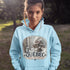 Person wearing a light blue hoodie with a Québec-themed design outdoors.