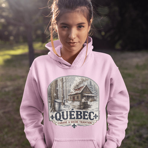 Person wearing a pink hoodie with a Québec-themed design outdoors.
