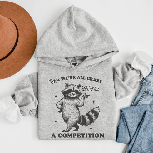 Meet your new spirit animal: a sassy raccoon with zero chill and a motto to live by: "Relax, we're all crazy—it’s not a competition."