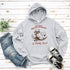 This hoodie features a raccoon—kicked back against a tree stump, wearing a cowboy hat, and looking like it just clocked out of life’s gym membership.