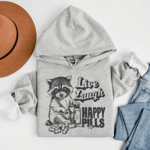 Introducing the "Live, Laugh, Happy Pills" Hoodie—because who better to take life advice from than a raccoon with a bottle of questionable pharmaceuticals? 🦝💊