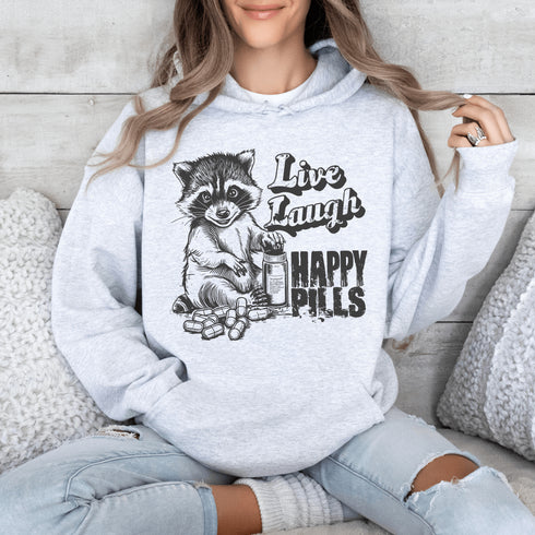Introducing the "Live, Laugh, Happy Pills" Hoodie—because who better to take life advice from than a raccoon with a bottle of questionable pharmaceuticals? 🦝💊