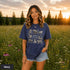 Vintage wildlife graphic on a pepper Comfort Colors t-shirt featuring a bear, fox, owl, squirrel, rabbit, deer, beaver, and lynx with the phrase "Respect the Locals," modeled in a wildflower meadow at sunset.