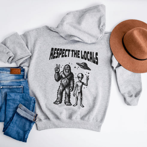 The Respect the Locals Hoodie features this dynamic duo (Big Foot & Alien) striking a pose like they’re on the cover of Paranormal Weekly