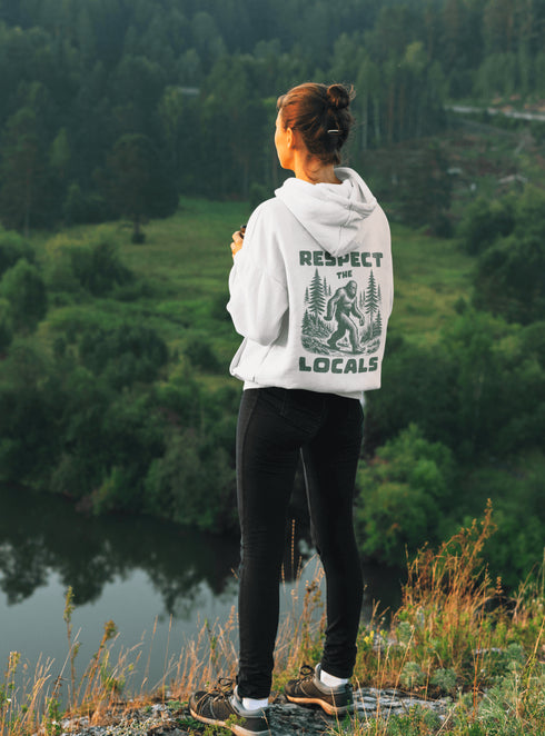 Our Respect the Locals Hoodie features the legend himself—Bigfoot—just casually strolling through the forest like it’s his backyard (because it is).