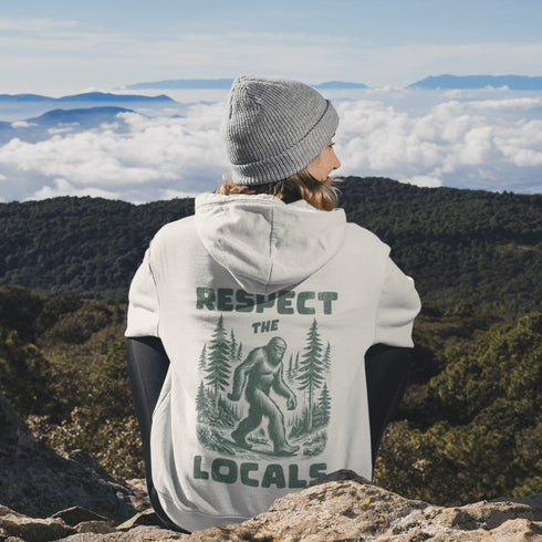 Our Respect the Locals Hoodie features the legend himself—Bigfoot—just casually strolling through the forest like it’s his backyard (because it is).