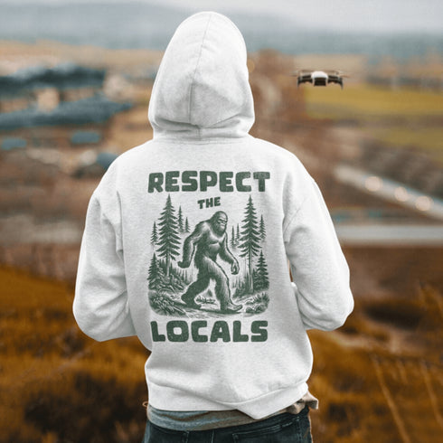 Our Respect the Locals Hoodie features the legend himself—Bigfoot—just casually strolling through the forest like it’s his backyard (because it is).
