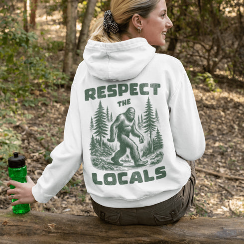 Our Respect the Locals Hoodie features the legend himself—Bigfoot—just casually strolling through the forest like it’s his backyard (because it is).