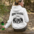 Our Respect the Locals Hoodie features the ultimate forest hangout: Bigfoot and an alien, just two mysterious dudes chilling on logs around a crackling campfire.