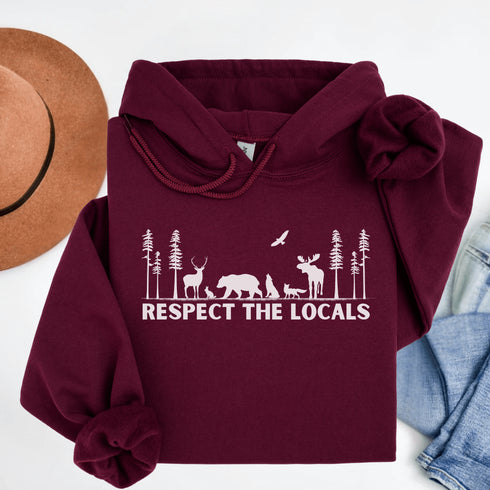 Step into the heart of the forest with our “Respect The Locals” hoodie, where artfully illustrated woodland animals roam under a canopy of trees.