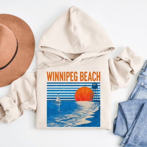 Capture the laid-back charm of lake life with our Winnipeg Beach hoodie. Featuring a vibrant graphic of the town’s iconic water tower set against a beach sunset