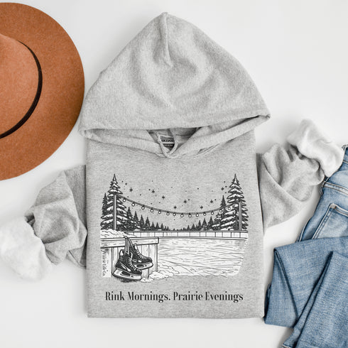 Cozy outdoor hockey hoodie featuring a glowing rink graphic and prairie winter vibe. Perfect for skating, cabin nights, and cold-weather comfort.