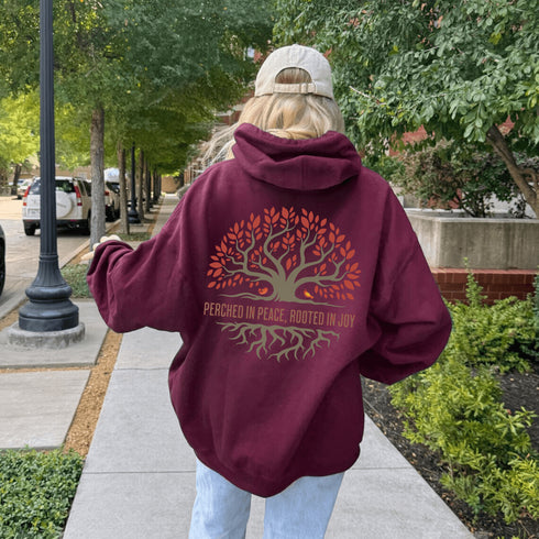 This design features a beautifully crafted tree with flowing roots, symbolizing strength and connection, paired with the uplifting saying, "Perched in peace, rooted in joy."