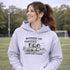 Soccer mom hoodie with “Running on Coffee and Game Day Chaos” design featuring moms cheering on the sidelines with kids playing soccer in the background