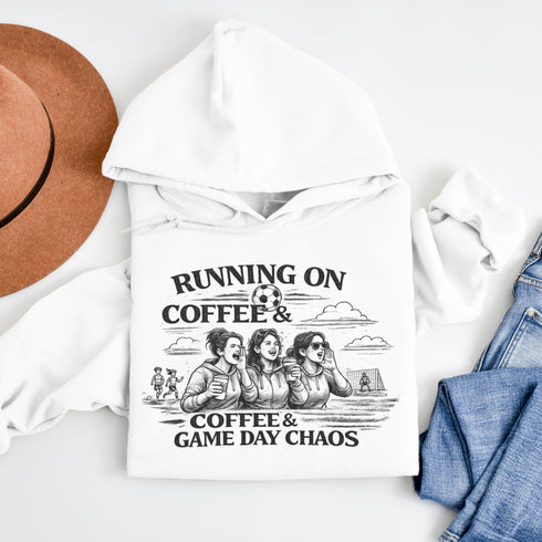 Soccer mom hoodie with “Running on Coffee and Game Day Chaos” design featuring moms cheering on the sidelines with kids playing soccer in the background