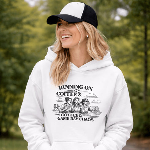 Soccer mom hoodie with “Running on Coffee and Game Day Chaos” design featuring moms cheering on the sidelines with kids playing soccer in the background