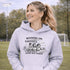 Soccer mom hoodie with “Running on Coffee and Game Day Chaos” design featuring moms cheering on the sidelines with kids playing soccer in the background