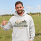 person wearing saskatchewan prairie life hoodie with farm and wheat field design standing in prairie field