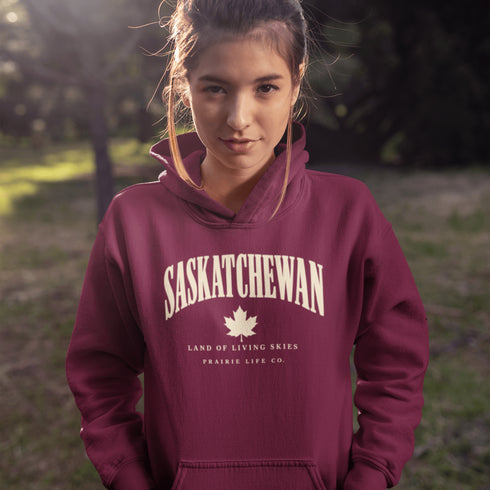 Saskatchewan Land of Living Skies unisex hoodie with vintage collegiate lettering and maple leaf graphic by Prairie Life Co.