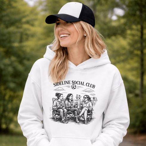 Soccer mom hoodie with “Sideline Social Club” design featuring moms sitting in lawn chairs drinking coffee while watching kids play soccer in the background