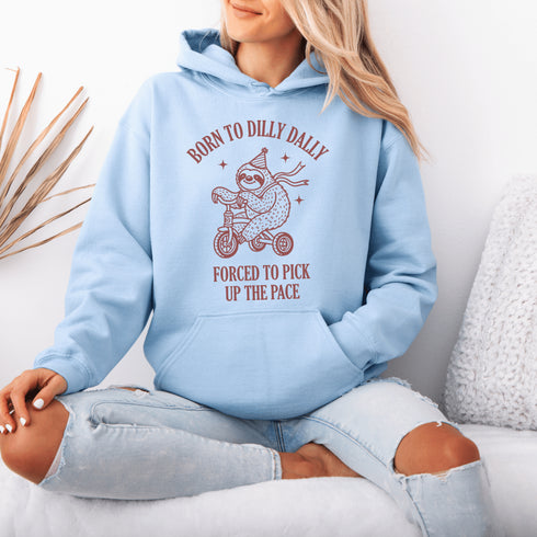 Say hello to the ultimate vibe hoodie: a chill sloth on a tricycle, rocking a party hat and scarf, paired with the painfully relatable words: "Born to dilly dally, forced to pick up the pace."