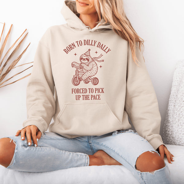 Say hello to the ultimate vibe hoodie: a chill sloth on a tricycle, rocking a party hat and scarf, paired with the painfully relatable words: "Born to dilly dally, forced to pick up the pace."