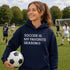 Person wearing “Soccer Is My Favorite Season” hoodie holding a soccer ball on a soccer field during a game, casual soccer apparel