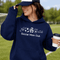 woman wearing soccer mom club hoodie with soccer icons design holding coffee at soccer field