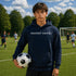 Person wearing “Soccer Nerd” hoodie holding a soccer ball on a soccer field during a game, casual athletic soccer apparel