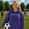 Person wearing “Soccer Nerd” hoodie holding a soccer ball on a soccer field during a game, casual athletic soccer apparel