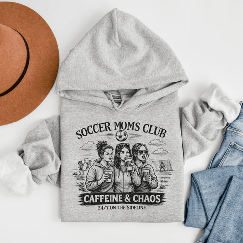 Soccer moms hoodie with “Soccer Moms Club Caffeine and Chaos” design featuring moms holding coffee cups and watching kids play soccer in the background