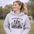 Soccer moms hoodie with “Soccer Moms Club Caffeine and Chaos” design featuring moms holding coffee cups and watching kids play soccer in the background