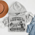 woman wearing grey hoodie with “Somebody’s Loud Mouth Soccer Mama” design featuring mom yelling on soccer sideline with kids playing in background
