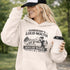 woman wearing grey hoodie with “Somebody’s Loud Mouth Soccer Mama” design featuring mom yelling on soccer sideline with kids playing in background