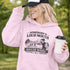 woman wearing grey hoodie with “Somebody’s Loud Mouth Soccer Mama” design featuring mom yelling on soccer sideline with kids playing in background