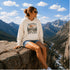 Vintage mountain adventure hoodie featuring a scenic outdoor landscape graphic on a Gildan 18500 Heavy Blend hoodie, shown in a lifestyle mockup. Available in multiple colors with a relaxed unisex fit.